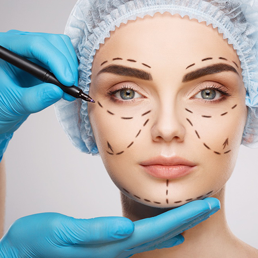 Surgeon marking a patient’s face with surgical guide lines